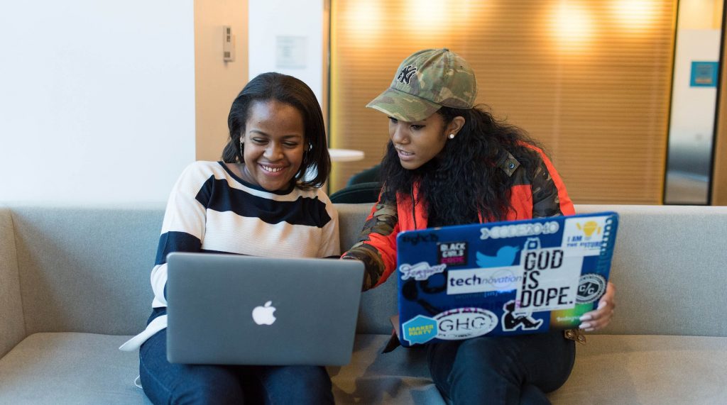 deux filles créant du contenu en ligne avec deux ordinateurs portables