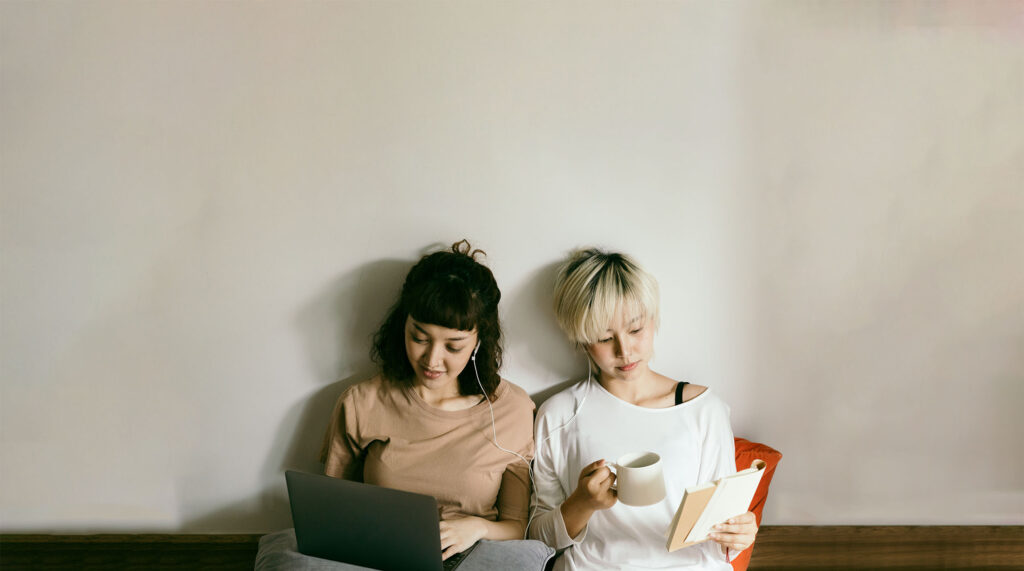 Deux jeunes femmes lisent en partageant une paire d’écouteurs pour illustrer cette liste des 10 posts les plus lus du blog de Genially.