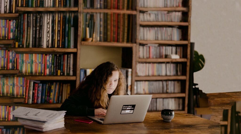 fille assise en train d'étudier avec un ordinateur portable dans une bibliothèque pour suggérer le concept de microlearning