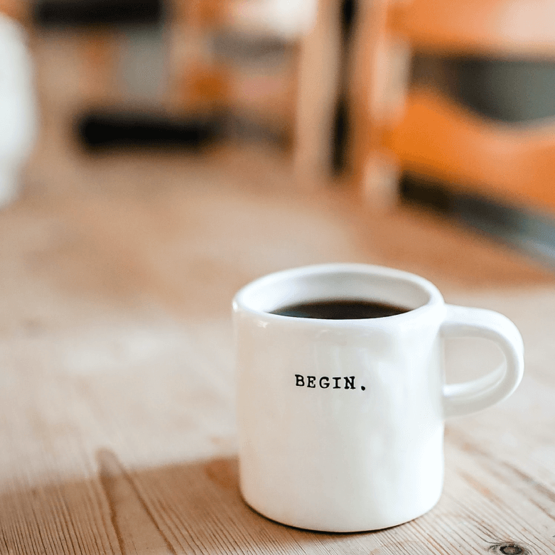 taza blanca con la palabra begin sobre una mesa